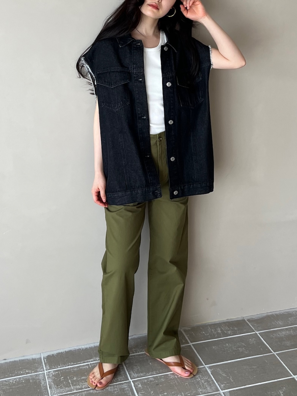 ブラック系のベスト、ホワイト系のタンクトップ、グリーン系のチノパンツを着用したレディースの春コーディネートの2枚目の写真