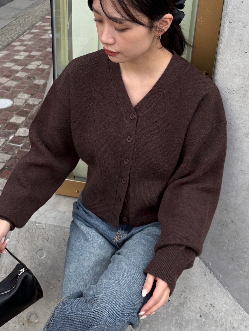 ブラウン系のカーディガン/ボレロ、ブルー系のデニムパンツ、ブラック系のショルダーバッグを着用したレディースの冬コーディネートの6枚目の写真