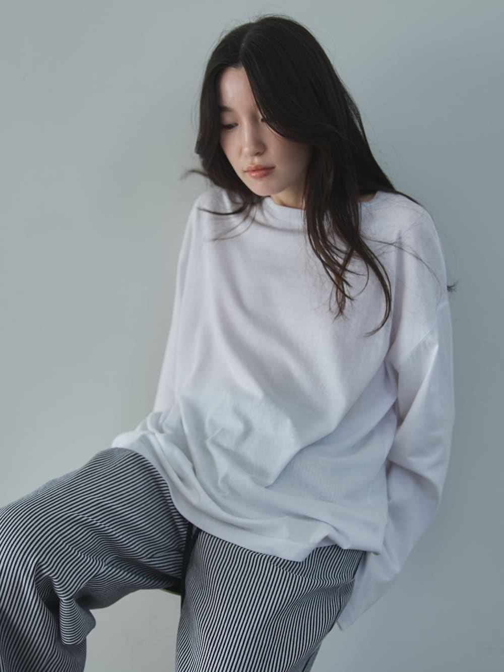 ホワイト系のTシャツ/カットソー、ホワイト系のデニムパンツ、ベージュ系のサンダルを着用したレディースの冬コーディネートの6枚目の写真