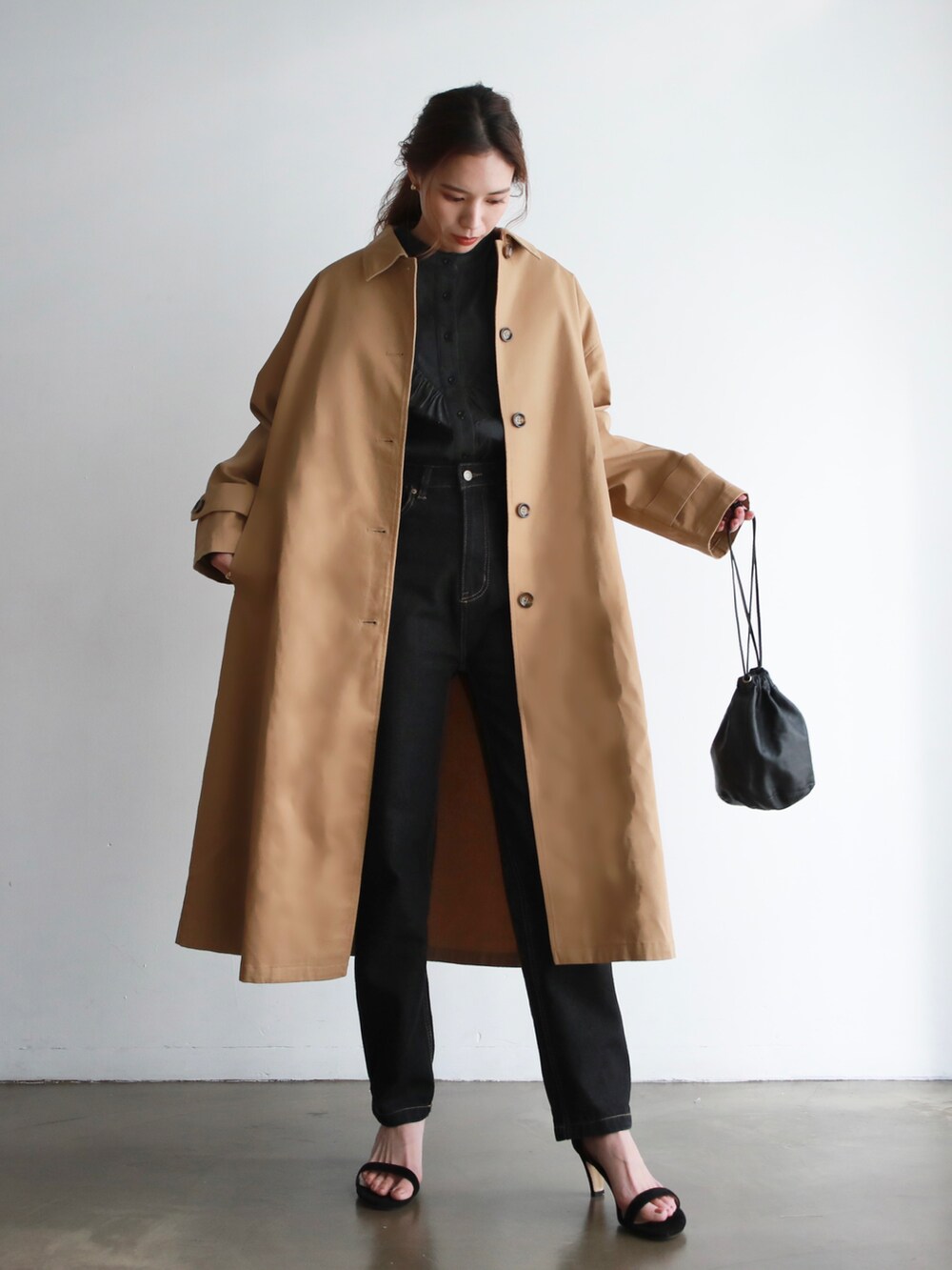 ホワイト系のステンカラーコート、ホワイト系のTシャツ/カットソー、ブラック系のハンドバッグを着用したレディースの冬コーディネートの3枚目の写真