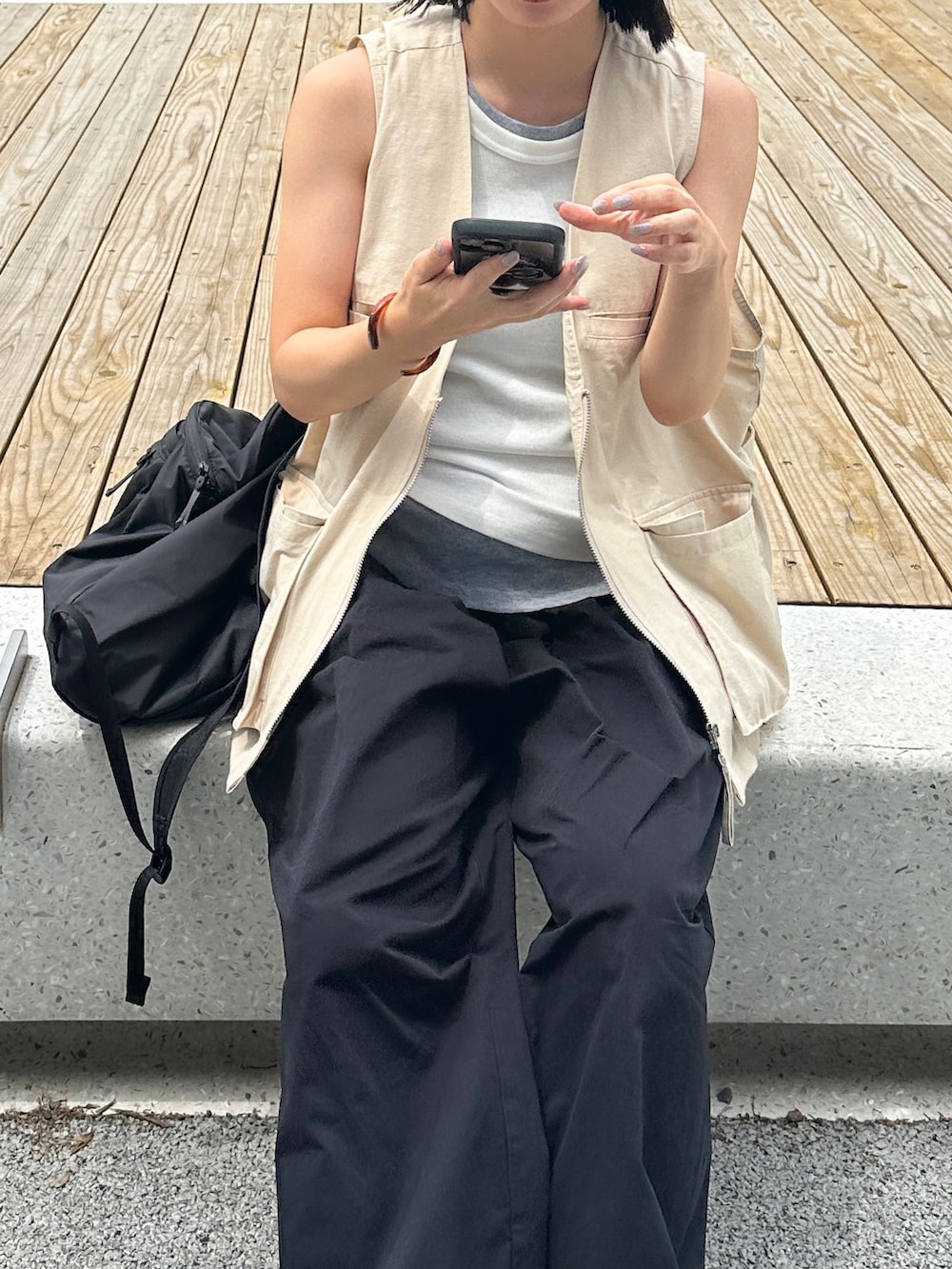ホワイト系のベスト、ブラック系のその他パンツ、グリーン系のスニーカーを着用したレディースの夏コーディネートの4枚目の写真