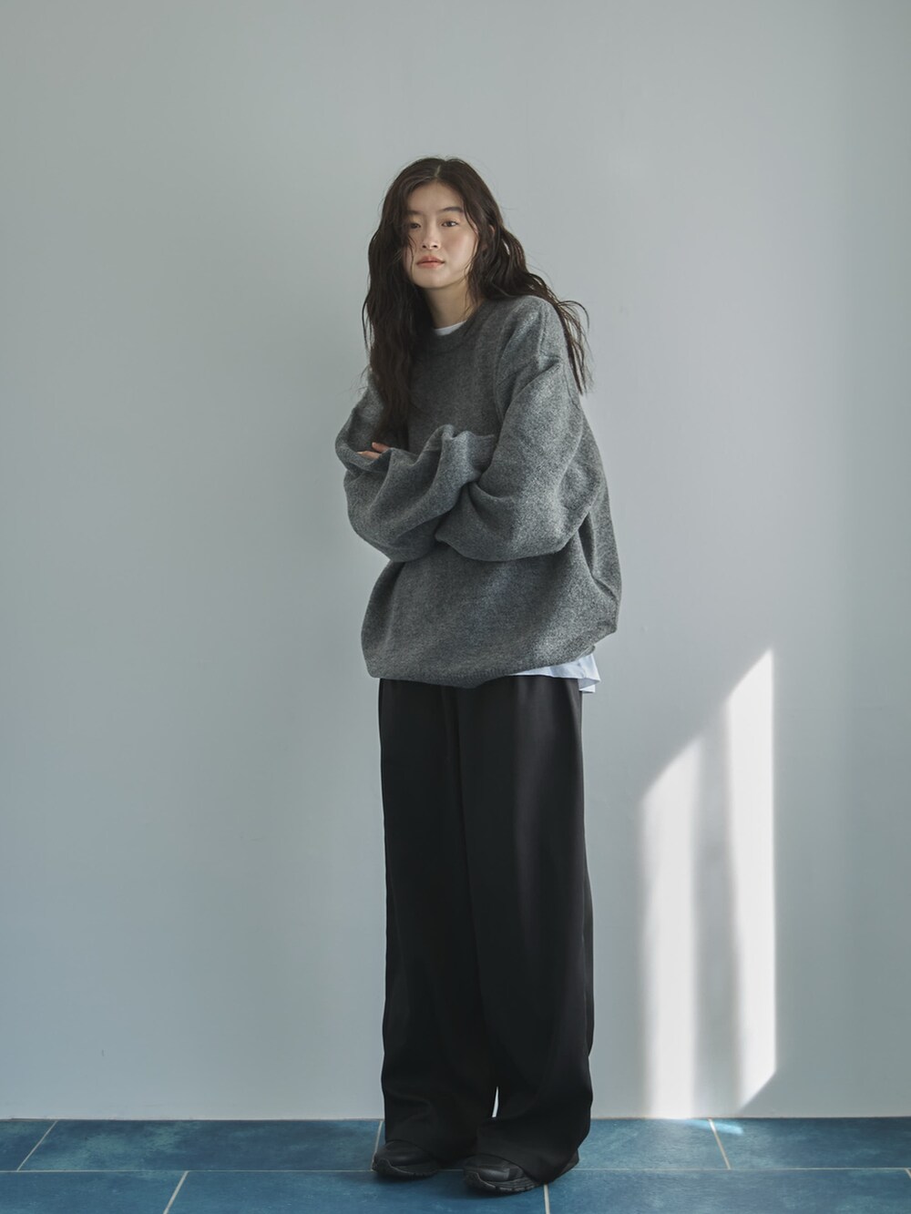 グレー系のニット/セーター、ホワイト系のTシャツ/カットソー、ブラック系のスラックスを着用したレディースの秋コーディネートの3枚目の写真