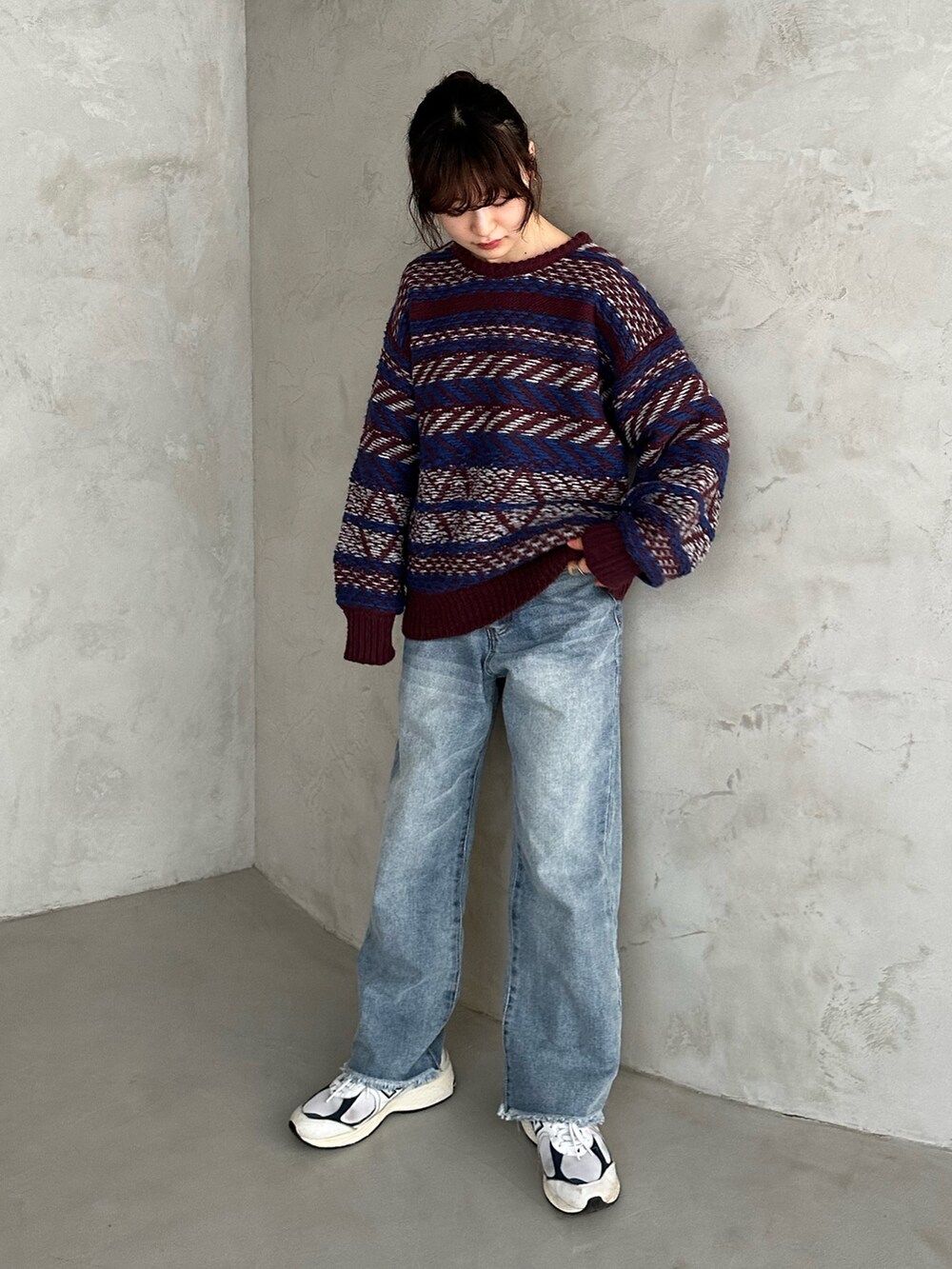 レッド系のニット/セーター、ブルー系のデニムパンツ、ホワイト系のスニーカーを着用したレディースの冬コーディネートの2枚目の写真