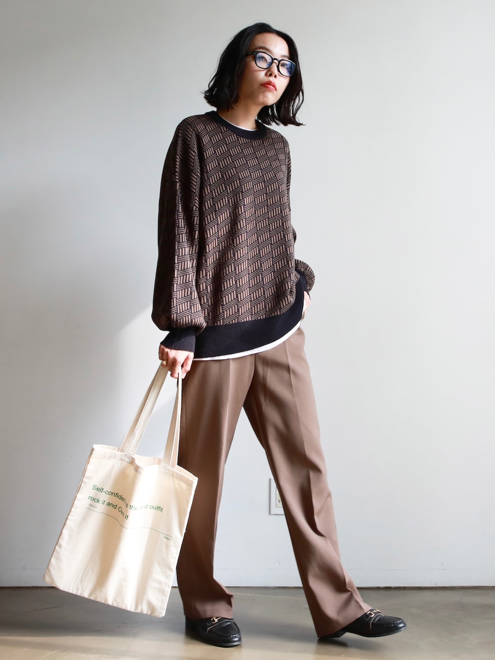 ブラック系のハンドバッグ、グリーン系のスカート、ブラック系のブーツを着用したレディースの秋コーディネートの2枚目の写真