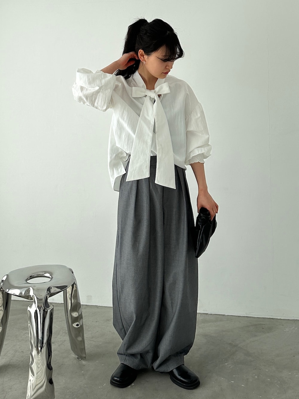 ホワイト系のシャツ/ブラウス、グレー系のスラックス、ブラック系のショルダーバッグを着用したレディースの冬コーディネートの2枚目の写真