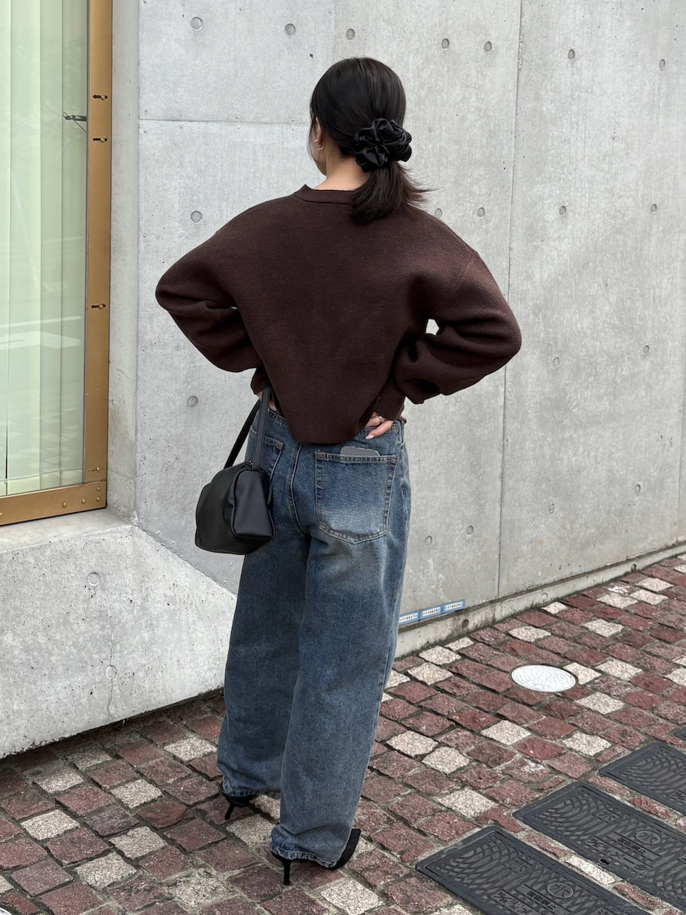 ブラウン系のカーディガン/ボレロ、ブルー系のデニムパンツ、ブラック系のショルダーバッグを着用したレディースの冬コーディネートの4枚目の写真