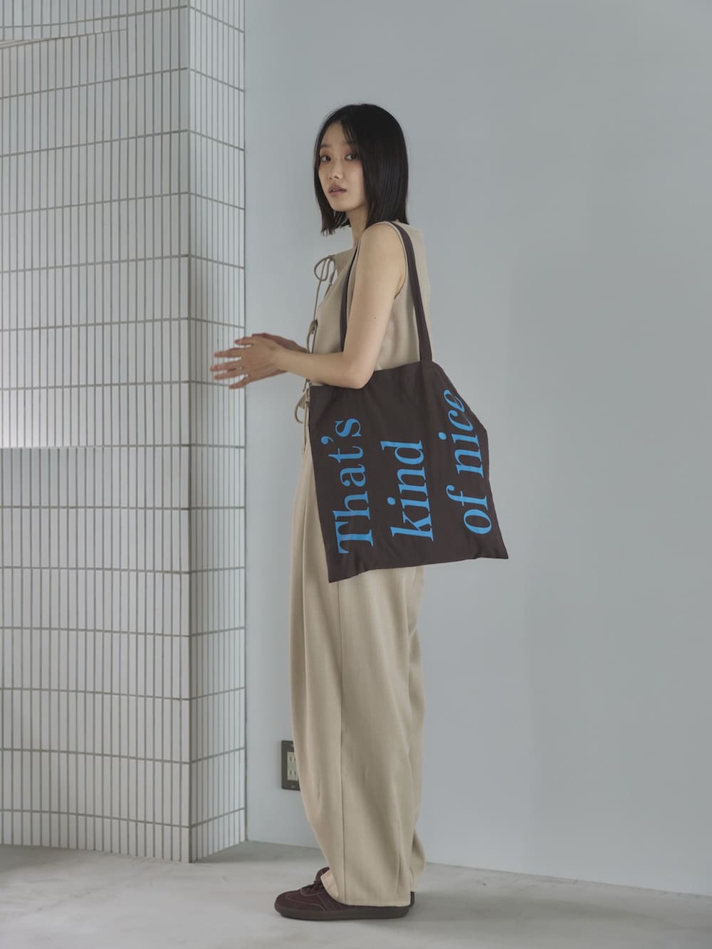 ホワイト系のスラックス、ホワイト系のベスト、ブラウン系のトートバッグを着用したレディースの夏コーディネートの2枚目の写真