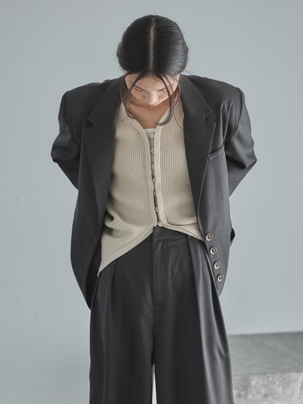 グレー系のテーラードジャケット、ホワイト系のカーディガン/ボレロ、グレー系のスラックスを着用したレディースの冬コーディネートの5枚目の写真