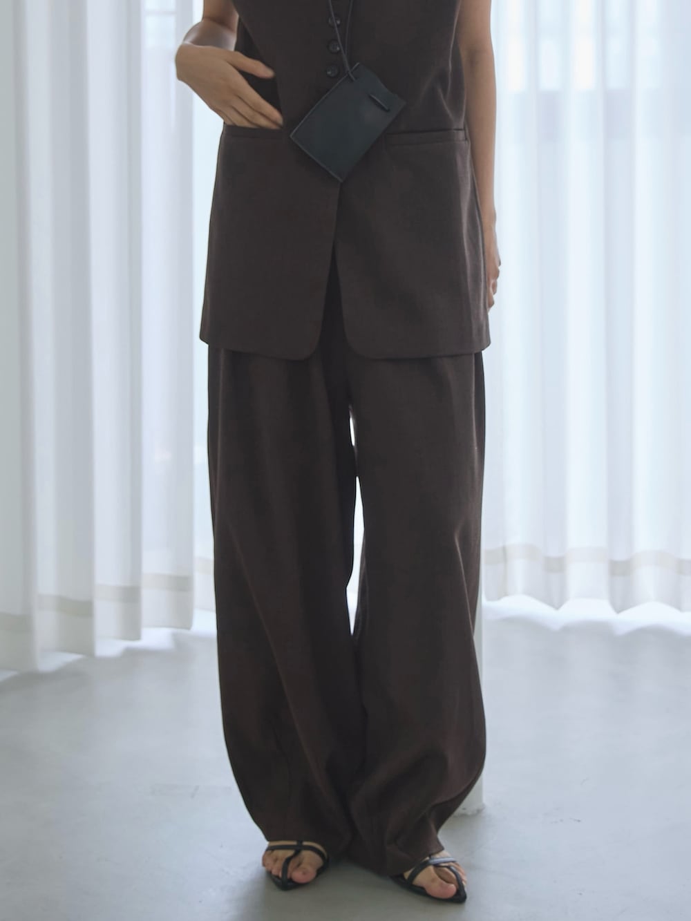 ブラウン系のベスト、ブラウン系のスラックス、ブラック系のサンダルを着用したレディースの夏コーディネートの5枚目の写真