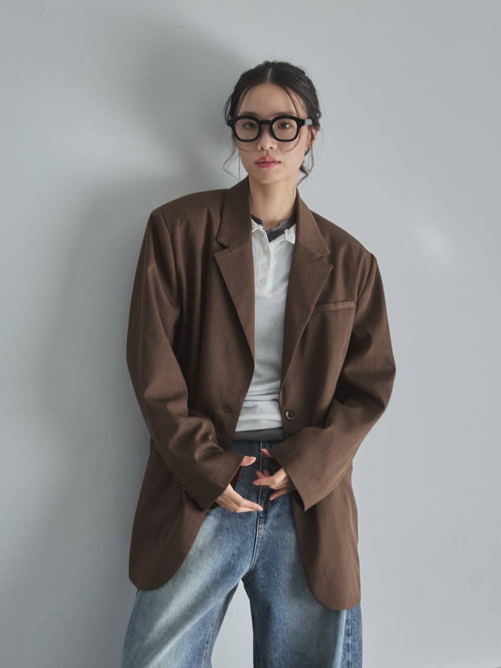 ブルー系のデニムパンツ、ブラウン系のテーラードジャケット、グレー系のTシャツ/カットソーを着用したレディースの春コーディネートの4枚目の写真