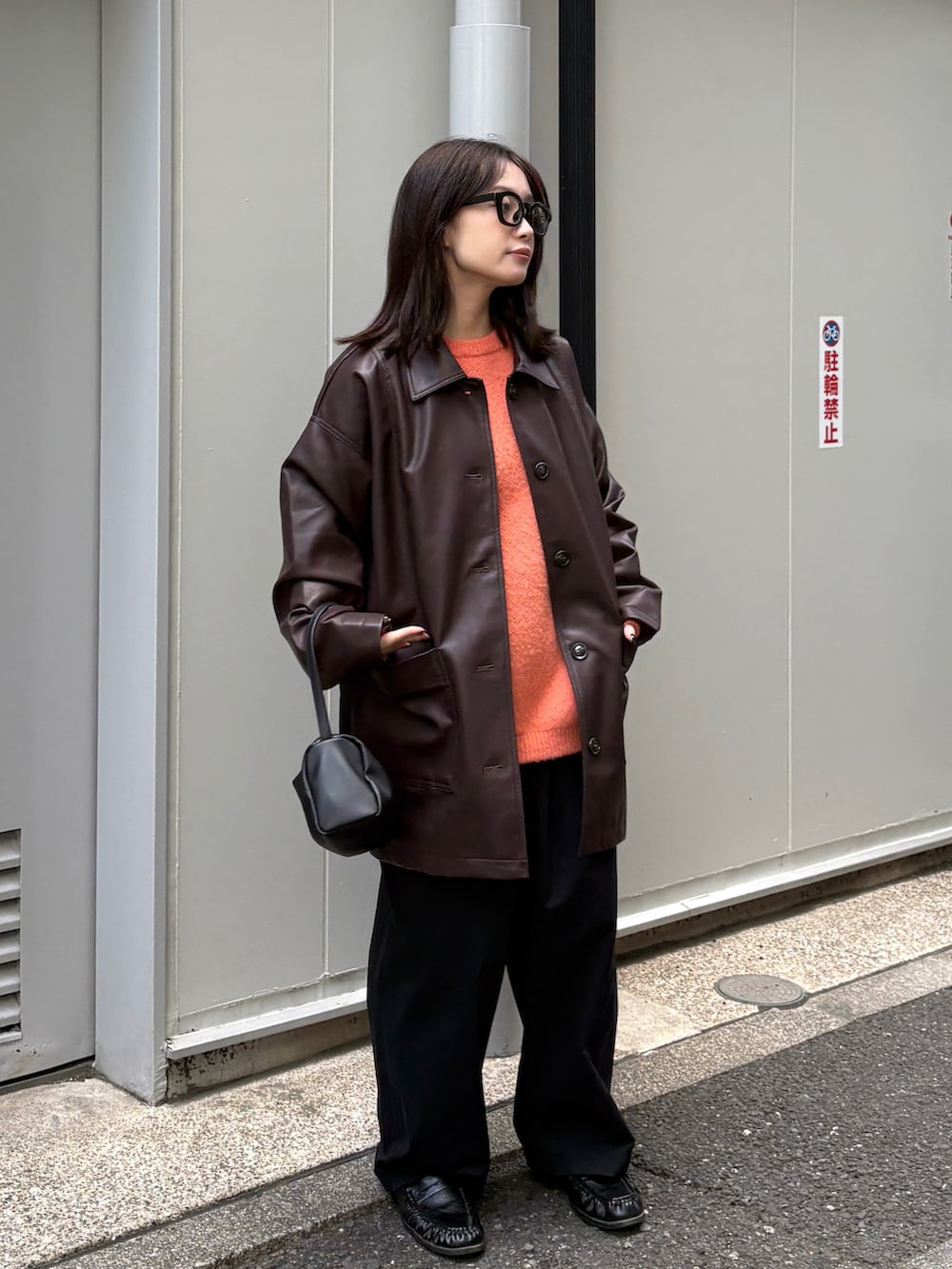 ブラウン系のカバーオール、オレンジ系のニット/セーター、ブラック系のショルダーバッグを着用したレディースの冬コーディネートの3枚目の写真