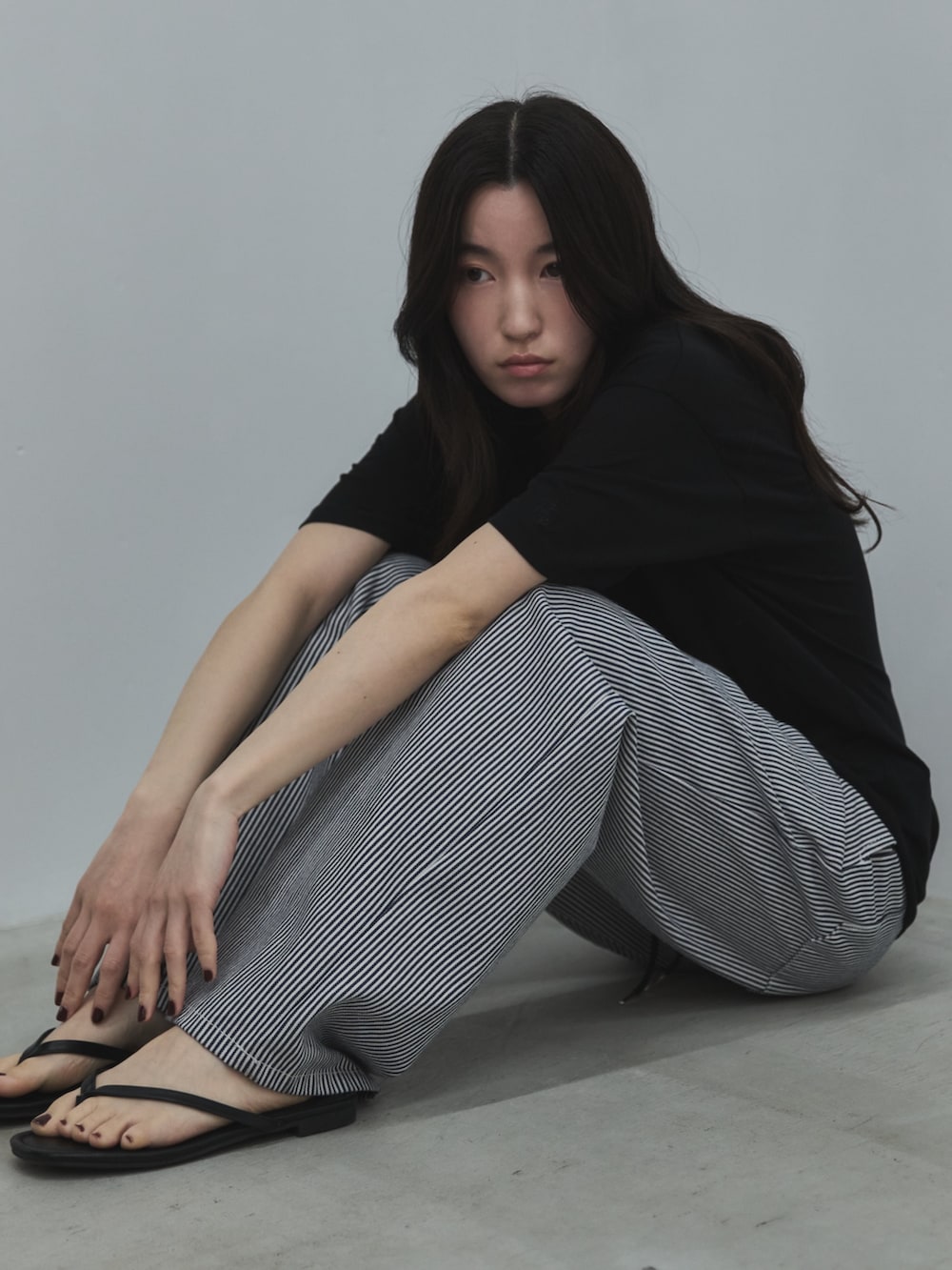 ブラック系のTシャツ/カットソー、ブラック系のデニムパンツ、ブラック系のサンダルを着用したレディースの春コーディネートの5枚目の写真