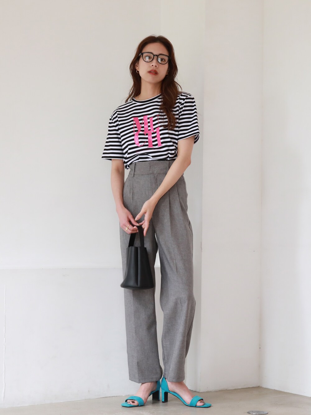 ブルー系のサンダル、ブラック系のショルダーバッグ、グレー系のスラックスを着用したレディースの夏コーディネートの2枚目の写真