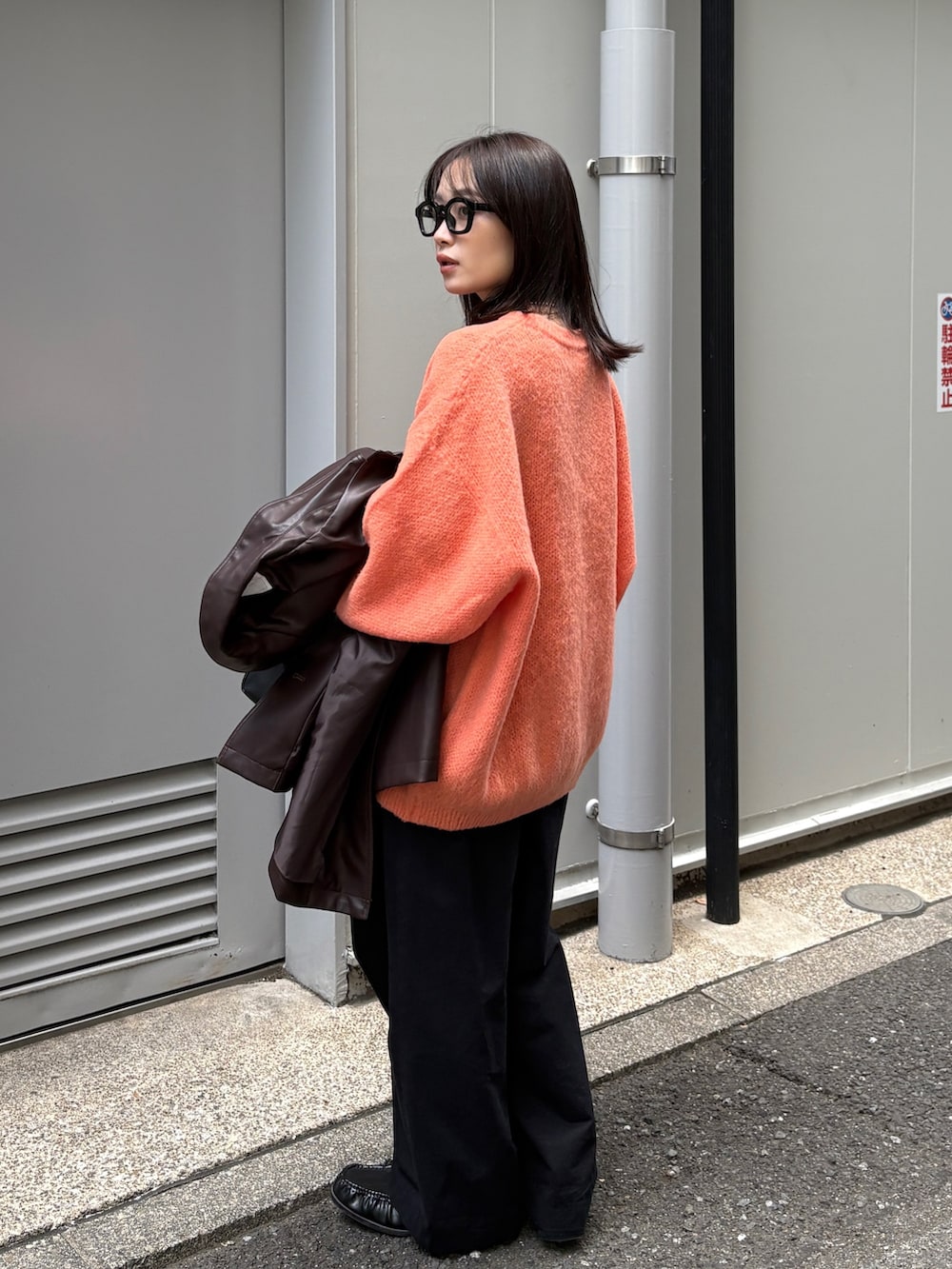 ブラウン系のカバーオール、オレンジ系のニット/セーター、ブラック系のショルダーバッグを着用したレディースの冬コーディネートの5枚目の写真