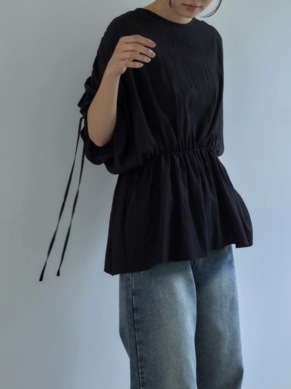 ブラック系のシャツ/ブラウス、ブルー系のデニムパンツ、ベージュ系のスニーカーを着用したレディースの夏コーディネートの5枚目の写真