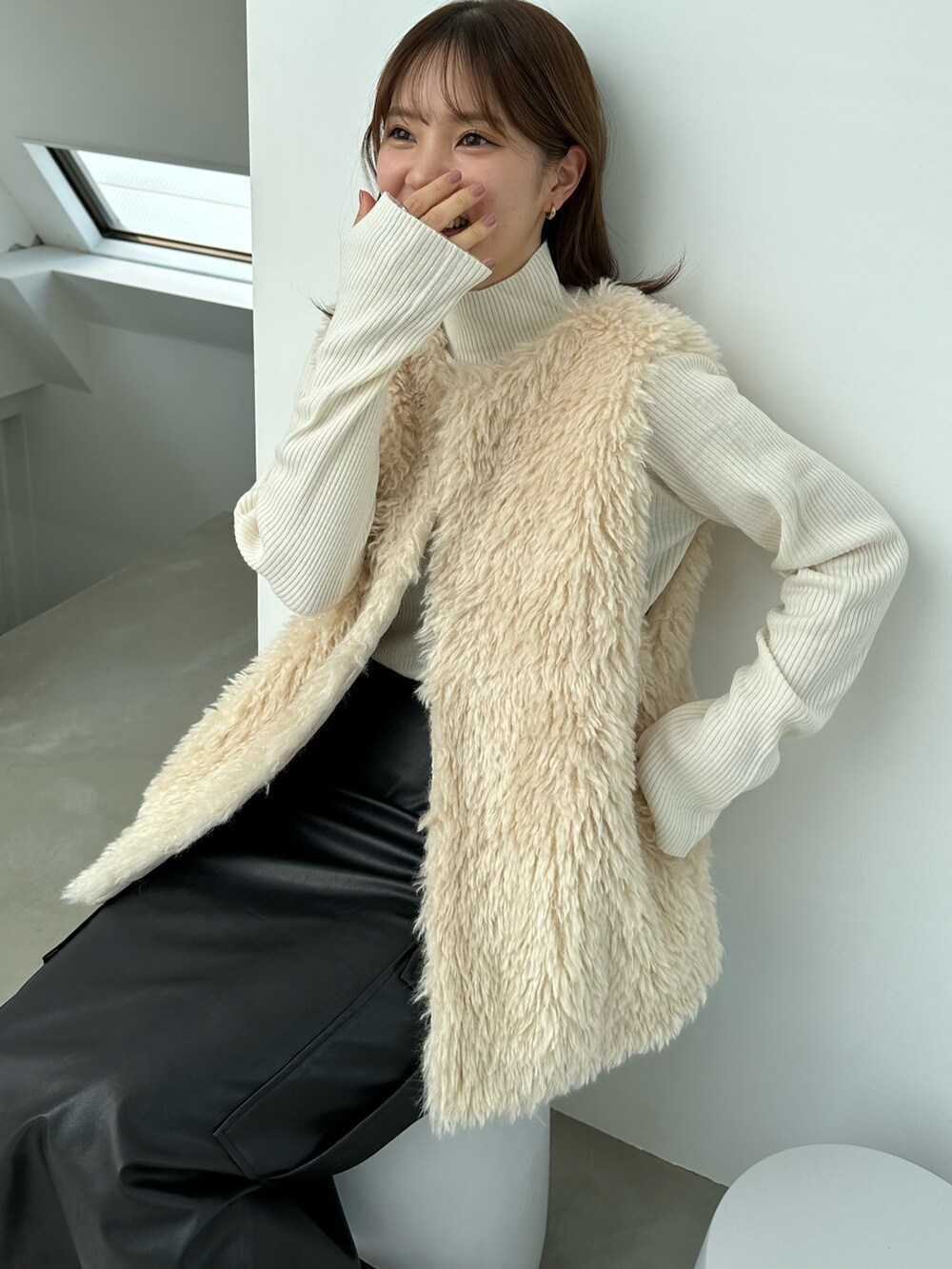 ホワイト系のベスト、ホワイト系のニット/セーター、ブラック系のスカートを着用したレディースの秋コーディネートの2枚目の写真