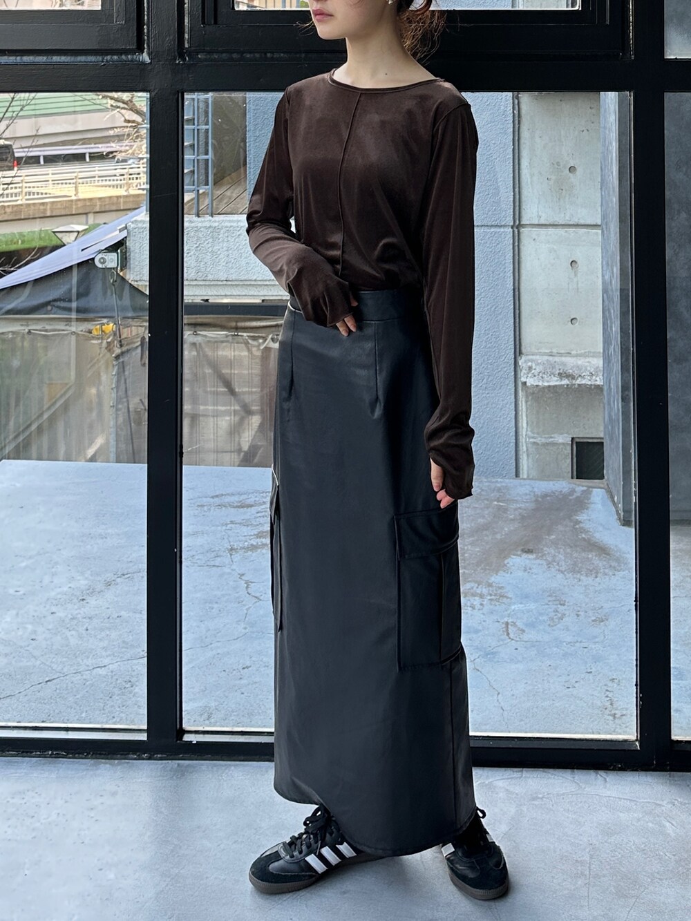 ブラウン系のTシャツ/カットソー、ブラック系のスカート、ブラック系のスニーカーを着用したレディースの冬コーディネートの3枚目の写真