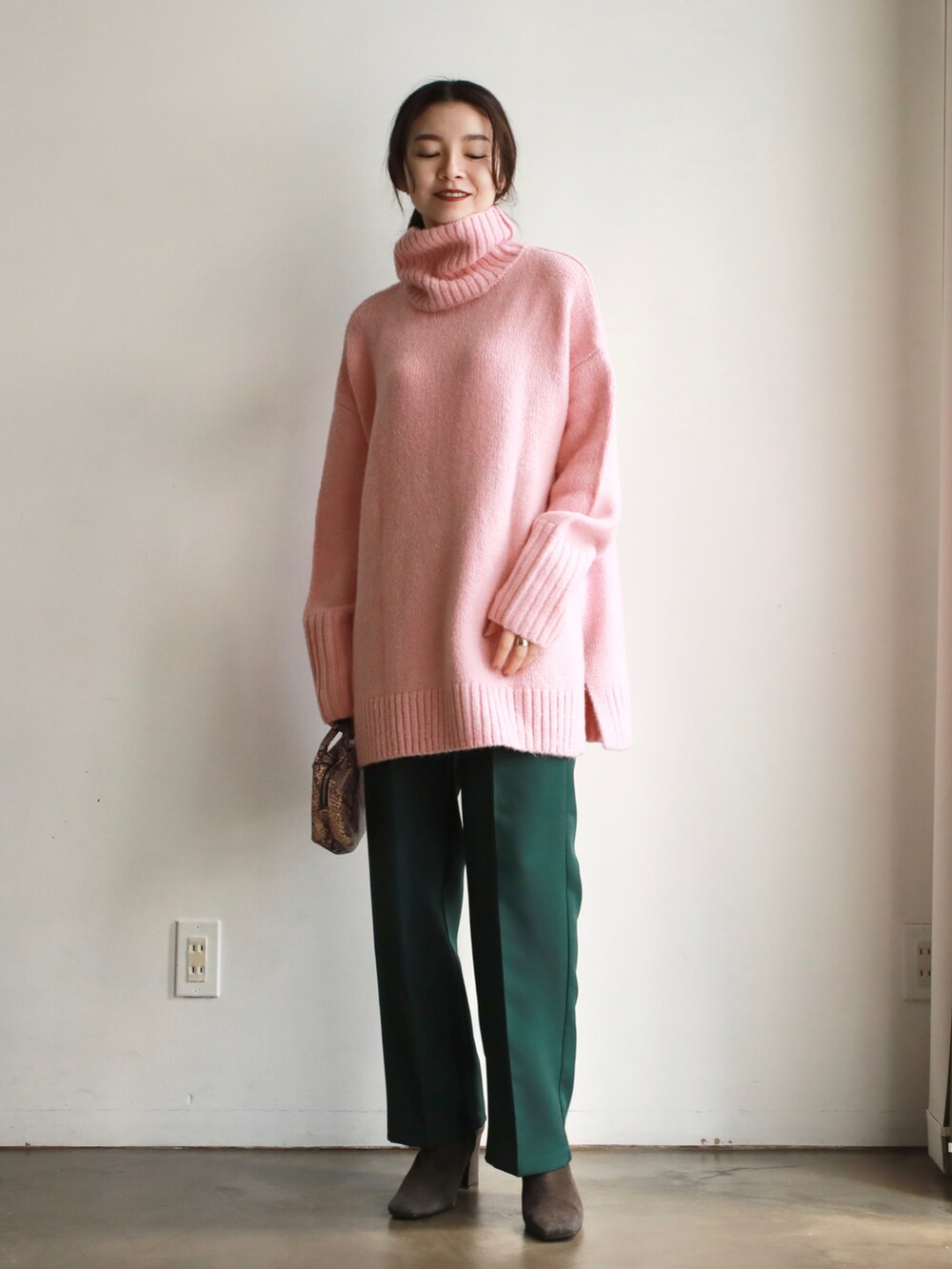 ブラウン系のハンドバッグ、ホワイト系のニット/セーター、ゴールド系のバレエシューズを着用したレディースの冬コーディネートの2枚目の写真