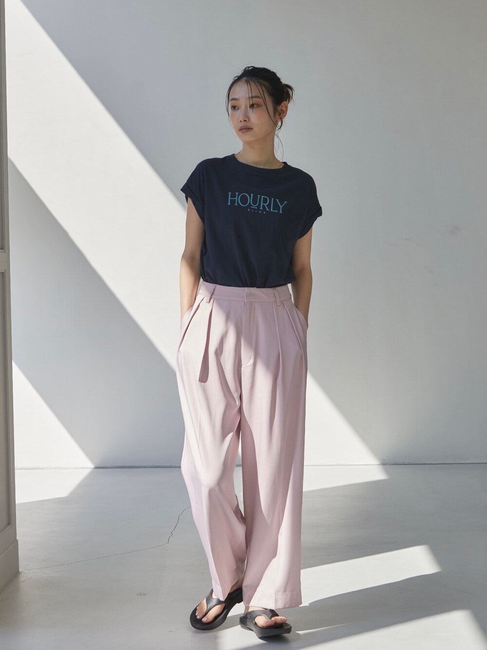 ピンク系のスラックス、ブルー系のTシャツ/カットソー、ブラック系のサンダルを着用したレディースの夏コーディネートの2枚目の写真