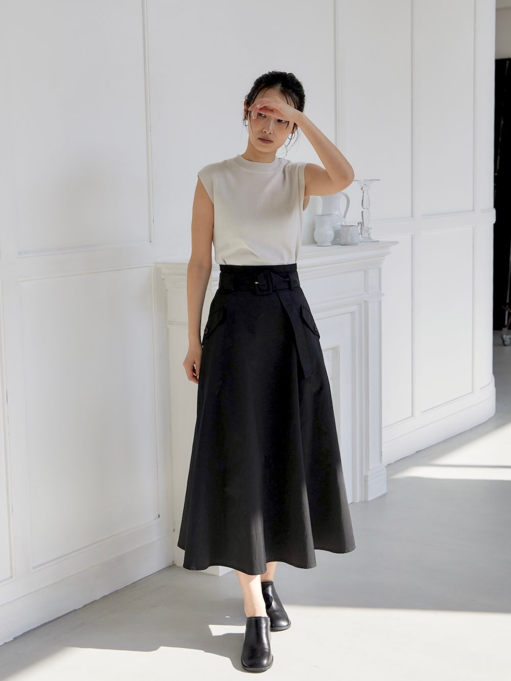 ブラック系のスカート、ホワイト系のニット/セーター、ブラック系のスリッポンを着用したレディースの夏コーディネートの2枚目の写真