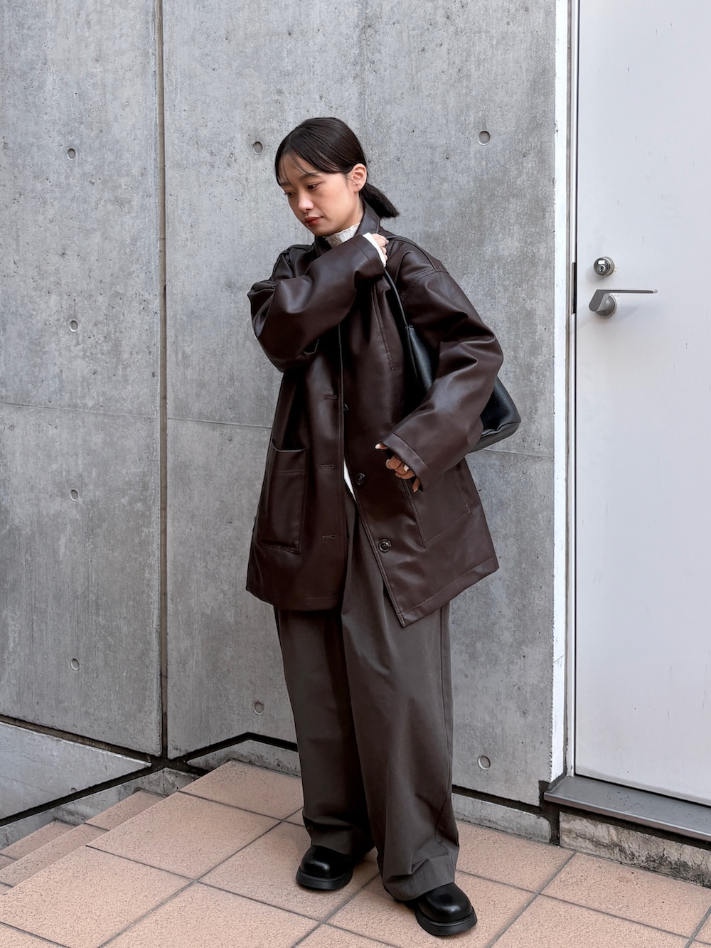 ブラウン系のカバーオール、ホワイト系のカーディガン/ボレロ、ブラック系のショルダーバッグを着用したレディースの春コーディネートの3枚目の写真