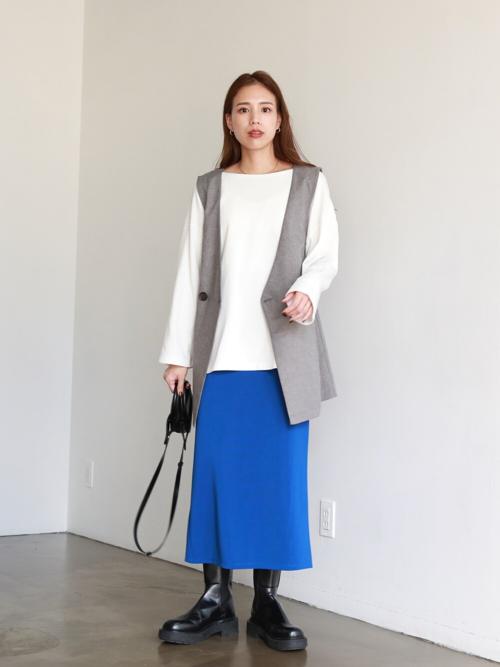 ブルー系のスカート、ホワイト系のTシャツ/カットソー、グレー系のベストを着用したレディースの夏コーディネートの2枚目の写真