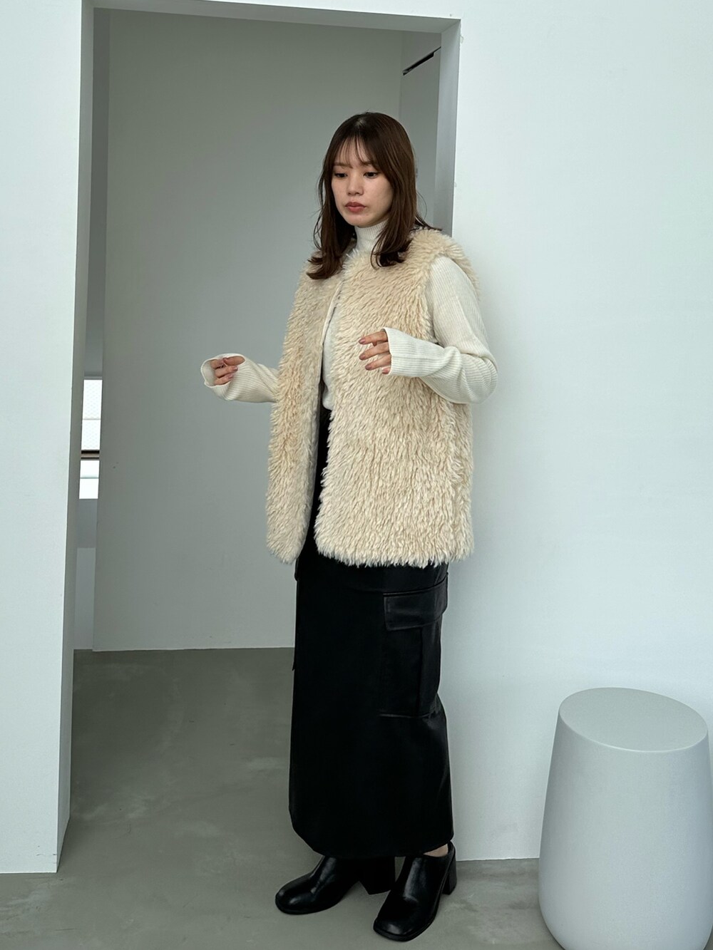 ホワイト系のベスト、ホワイト系のニット/セーター、ブラック系のスカートを着用したレディースの秋コーディネートの4枚目の写真