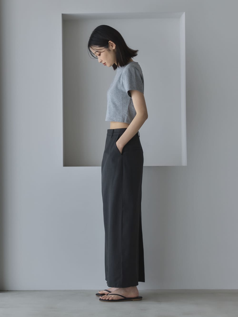 グレー系のTシャツ/カットソー、グレー系のスカート、ブラック系のサンダルを着用したレディースの夏コーディネートの4枚目の写真