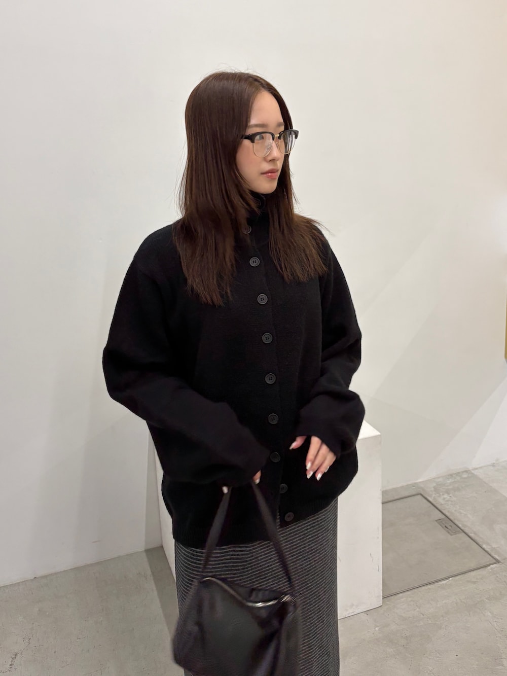 ブラック系のニット/セーター、グレー系のスカート、ブラック系のショルダーバッグを着用したレディースの秋コーディネートの3枚目の写真