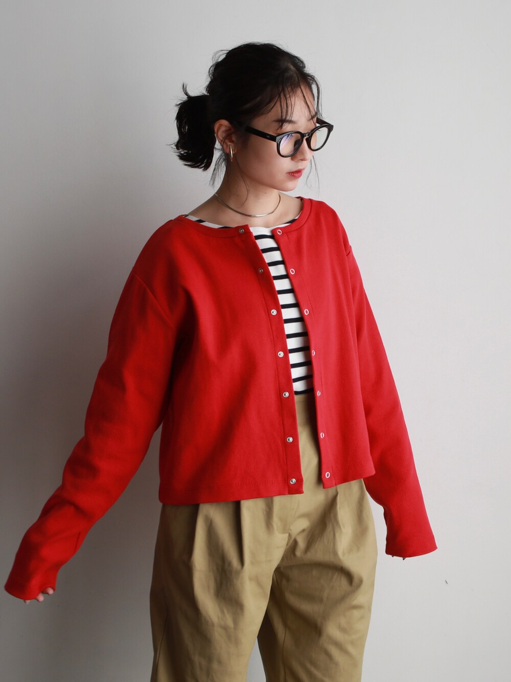 ブラック系のハンドバッグ、ベージュ系のチノパンツ、レッド系のカーディガン/ボレロを着用したレディースの冬コーディネートの2枚目の写真