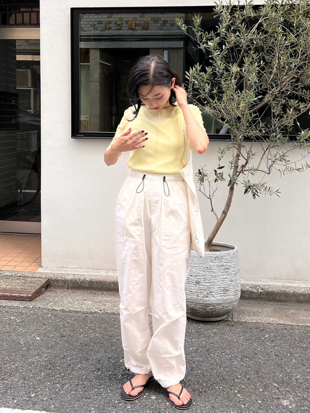 ブラック系のサンダル、ホワイト系のカーゴパンツ、ベージュ系のTシャツ/カットソーを着用したレディースの夏コーディネートの2枚目の写真