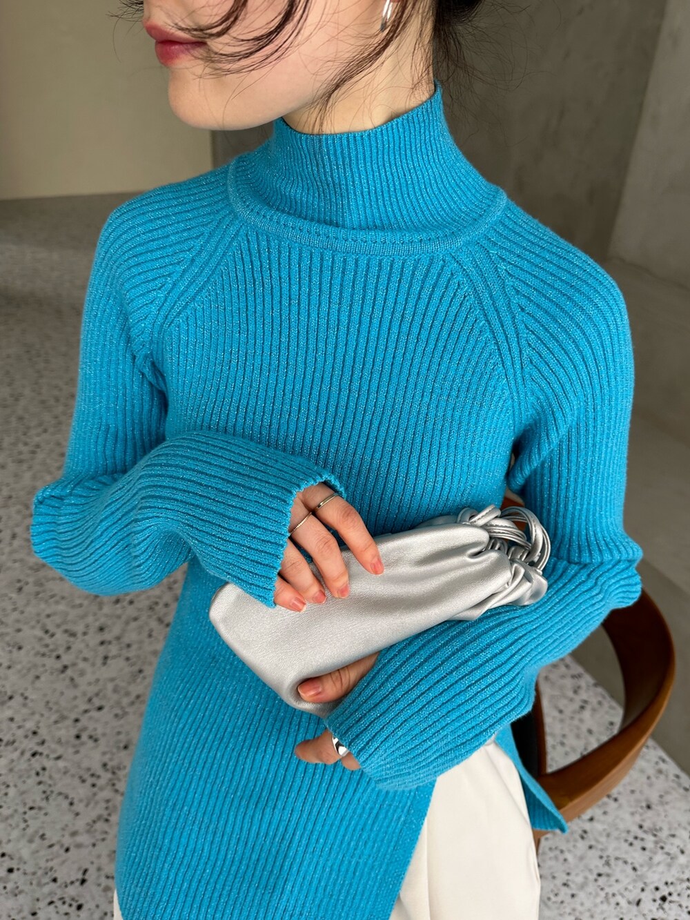 ブラック系のチェスターコート、ブルー系のニット/セーター、シルバー系のショルダーバッグを着用したレディースの冬コーディネートの5枚目の写真