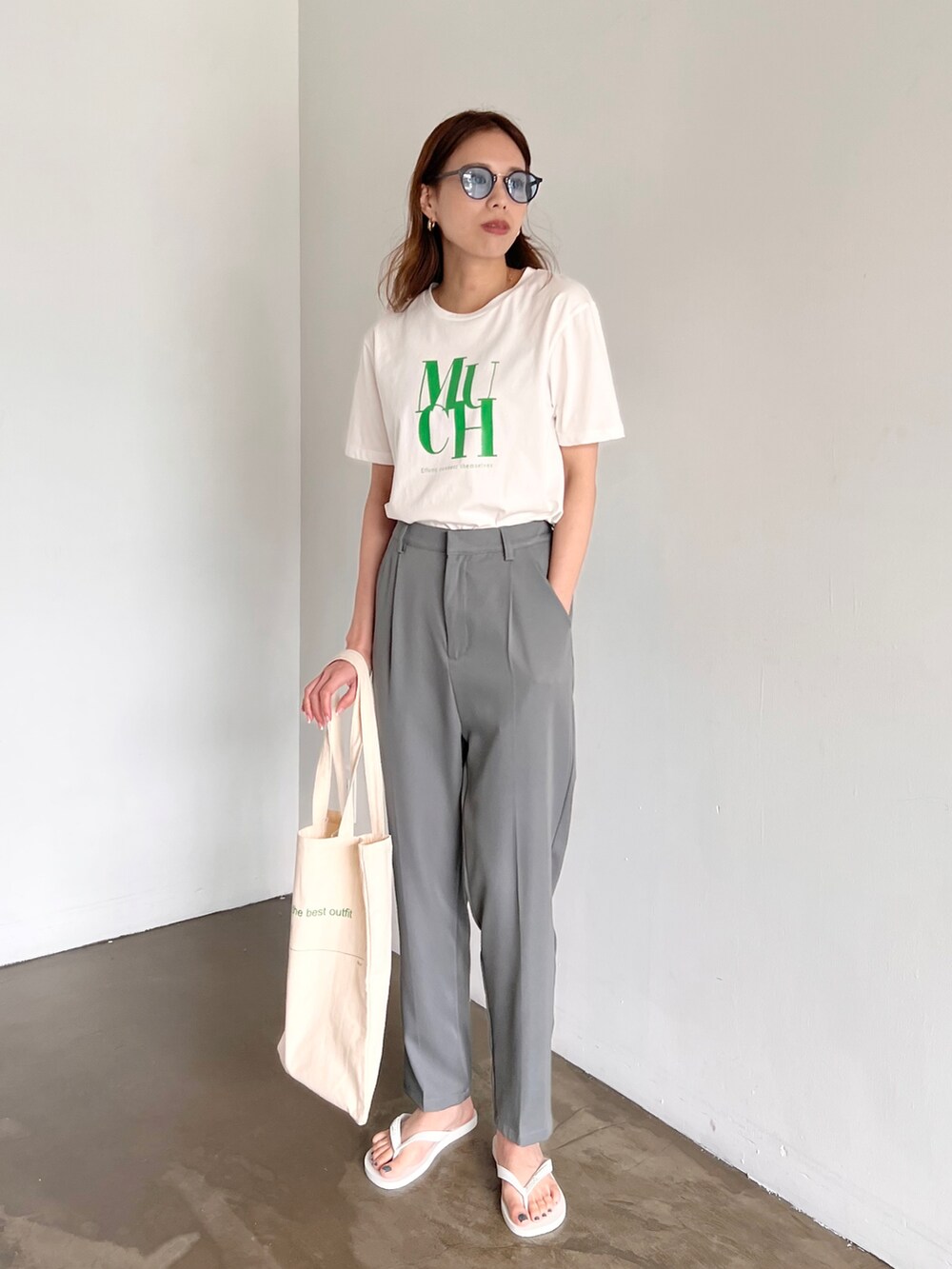 グレー系のスラックス、ホワイト系のトートバッグ、ホワイト系のTシャツ/カットソーを着用したレディースの夏コーディネートの2枚目の写真