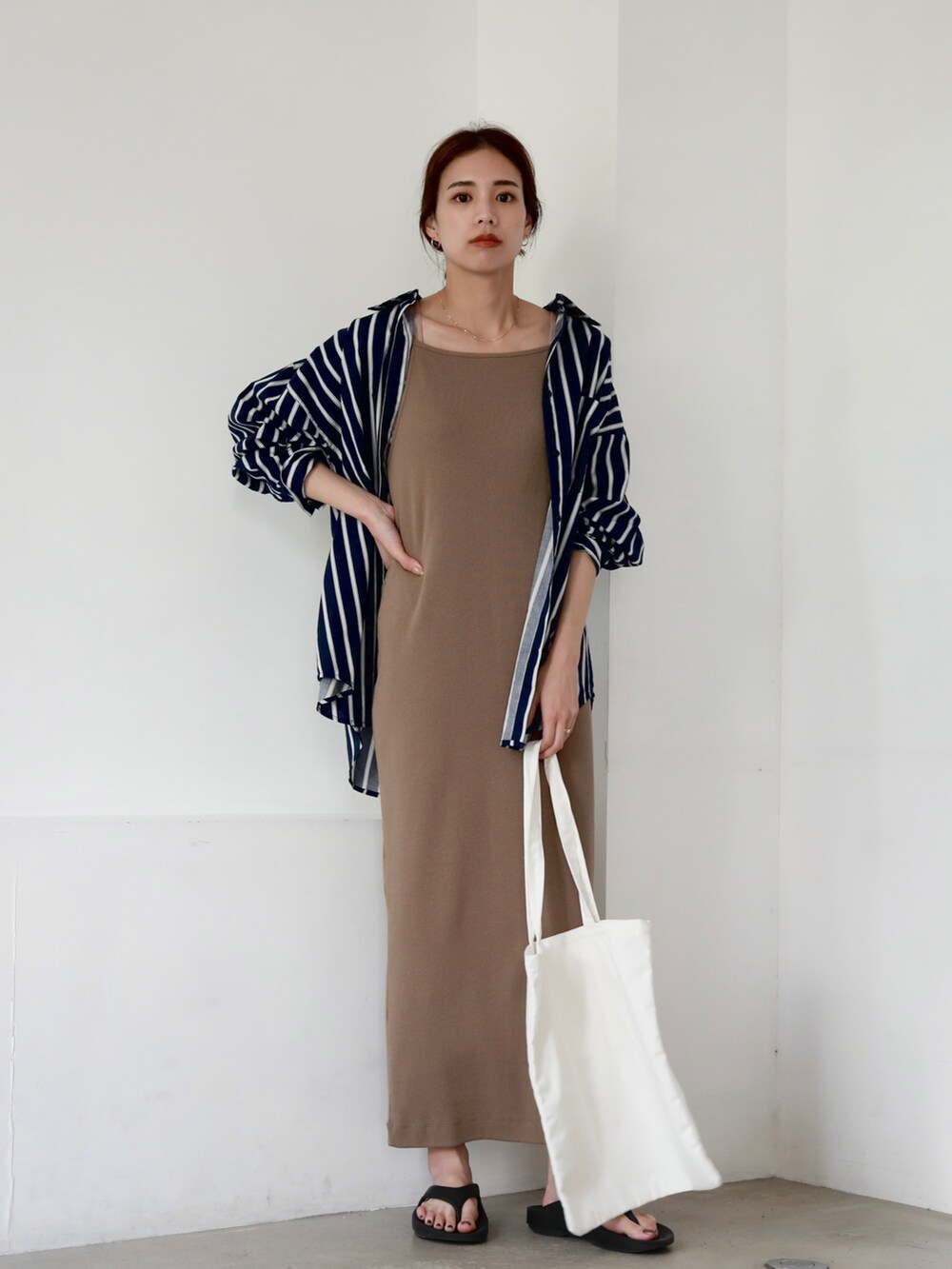 ホワイト系のトートバッグ、ブラック系のサンダル、ブラウン系のワンピースを着用したレディースの夏コーディネートの2枚目の写真