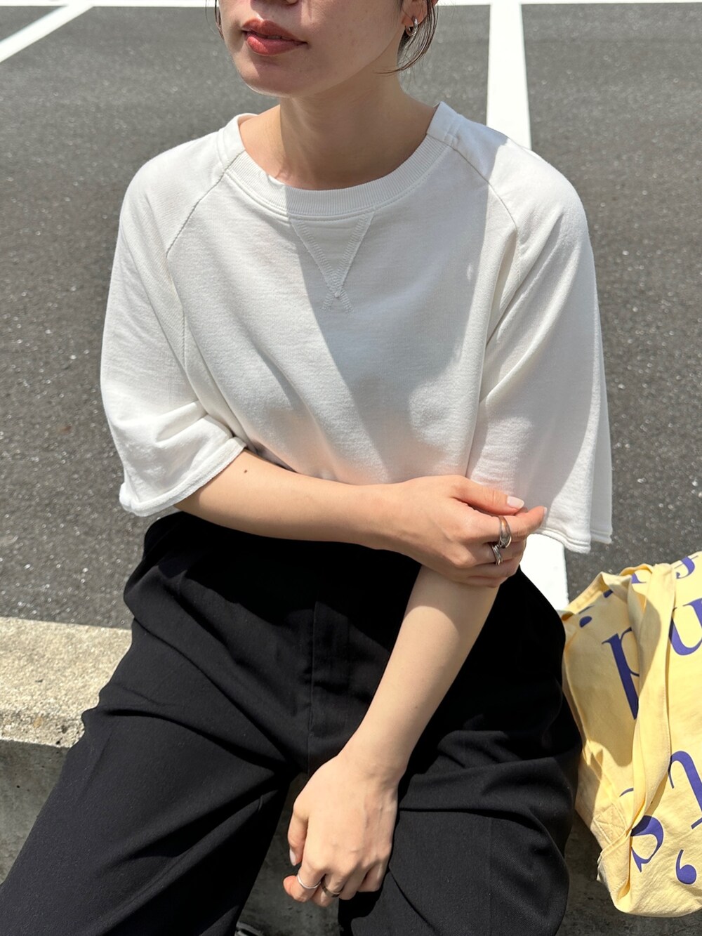 ホワイト系のTシャツ/カットソー、イエロー系のトートバッグ、ホワイト系のスニーカーを着用したレディースの夏コーディネートの3枚目の写真