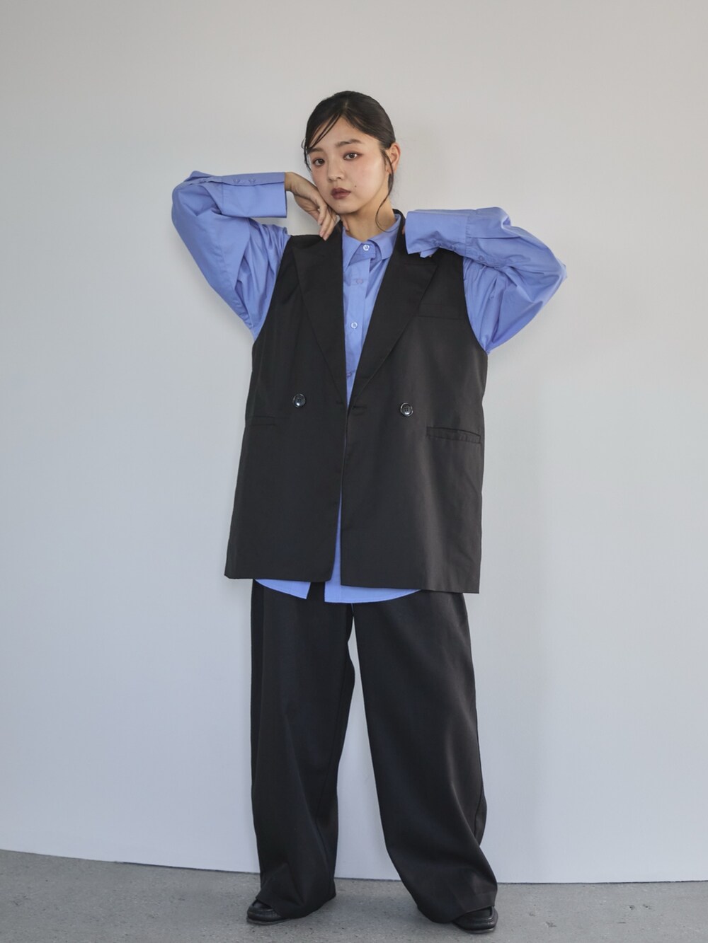 ブラック系のベスト、ブルー系のシャツ/ブラウス、ブラック系のスラックスを着用したレディースの冬コーディネートの2枚目の写真