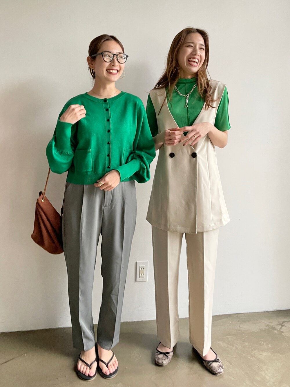 グレー系のスラックス、グリーン系のカーディガン/ボレロ、ホワイト系のセットアップを着用したレディースの春コーディネートの2枚目の写真