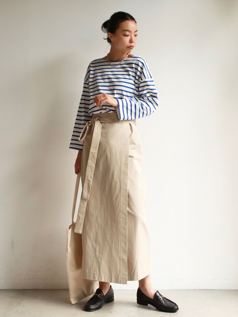 グリーン系のTシャツ/カットソー、ベージュ系のスカート、ブラック系のスニーカーを着用したレディースの冬コーディネートの5枚目の写真