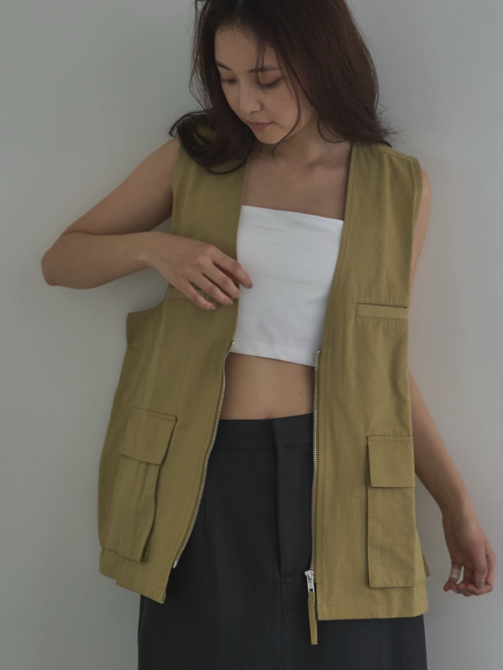 ホワイト系のキャミソール、ベージュ系のベスト、ブラック系のサンダルを着用したレディースの夏コーディネートの4枚目の写真