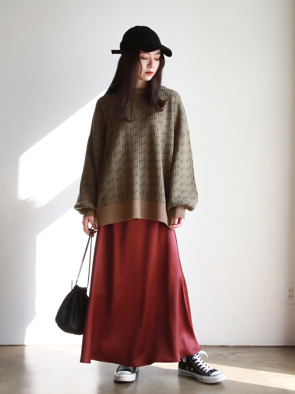 グリーン系のニット/セーター、ブラック系のハンドバッグ、レッド系のスカートを着用したレディースの秋コーディネートの2枚目の写真
