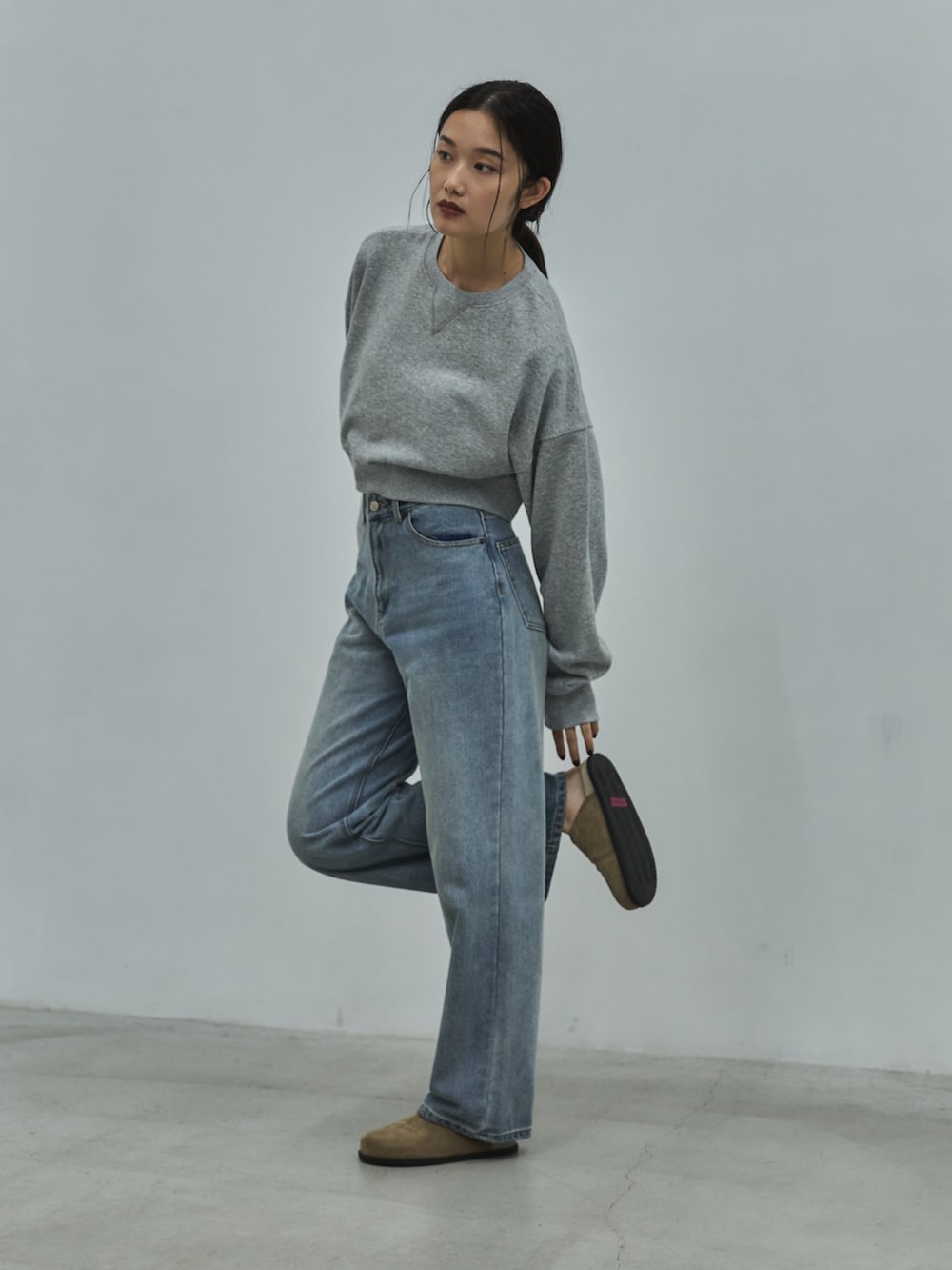 グレー系のスウェット、ブルー系のデニムパンツ、ベージュ系のその他シューズを着用したレディースの秋コーディネートの2枚目の写真