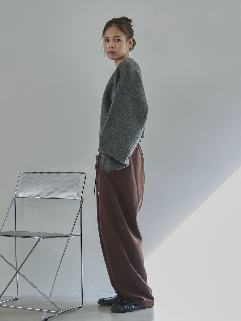 グレー系のニット/セーター、ブラウン系のその他パンツ、ブラック系のローファーを着用したレディースの冬コーディネートの3枚目の写真