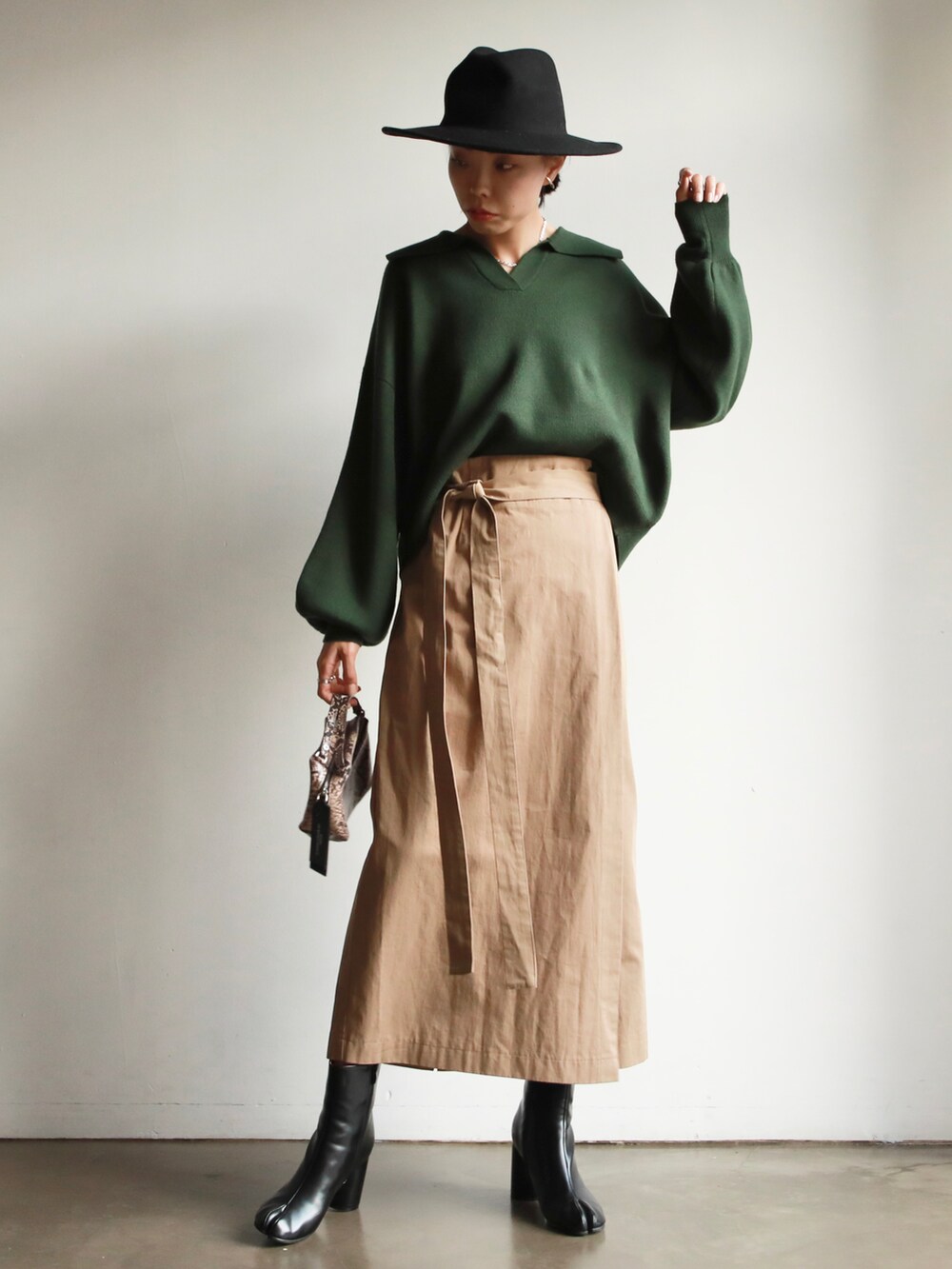 グリーン系のTシャツ/カットソー、ベージュ系のスカート、ブラック系のスニーカーを着用したレディースの冬コーディネートの2枚目の写真