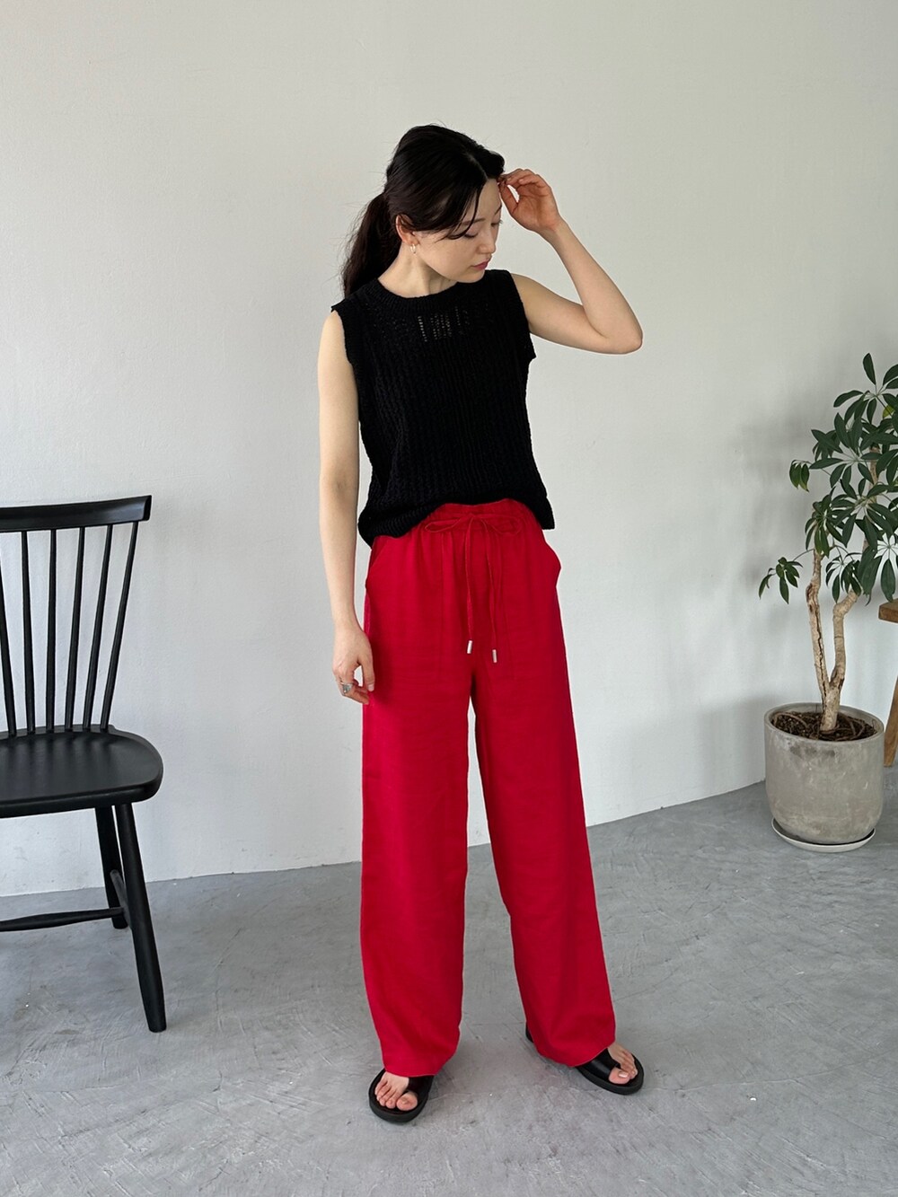 ブラック系のニット/セーター、レッド系のその他パンツ、ブラック系のサンダルを着用したレディースの夏コーディネートの2枚目の写真