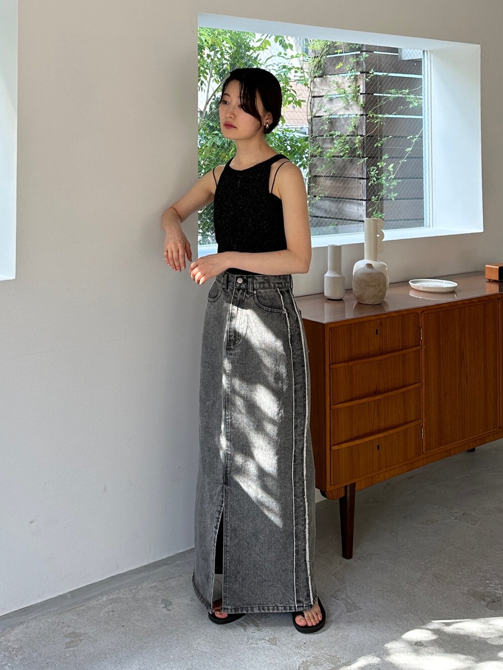 ブラック系のニット/セーター、グレー系のデニムスカート、ブラック系のサンダルを着用したレディースの夏コーディネートの2枚目の写真