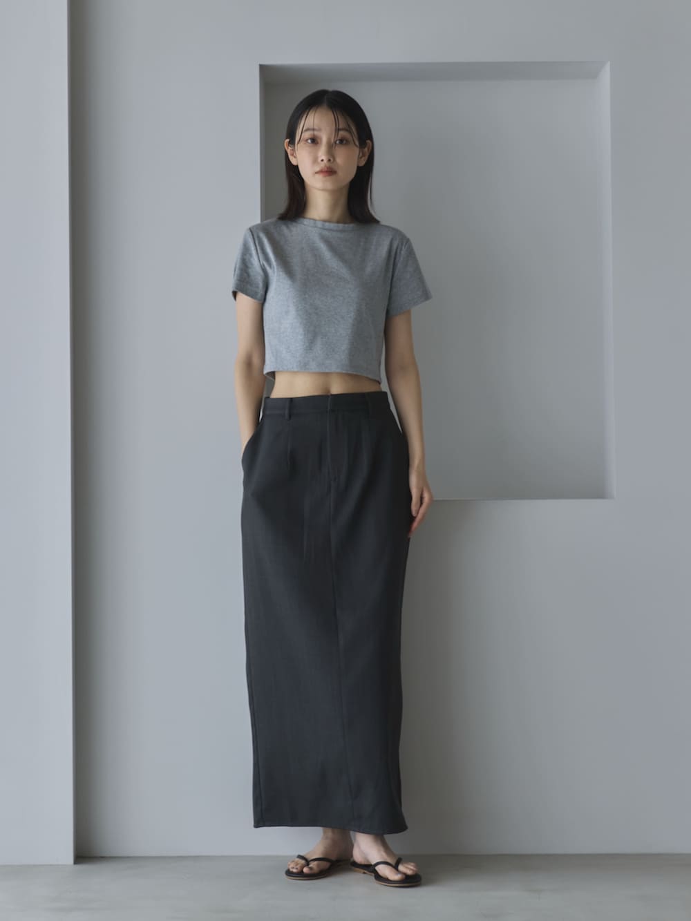 グレー系のTシャツ/カットソー、グレー系のスカート、ブラック系のサンダルを着用したレディースの夏コーディネートの2枚目の写真