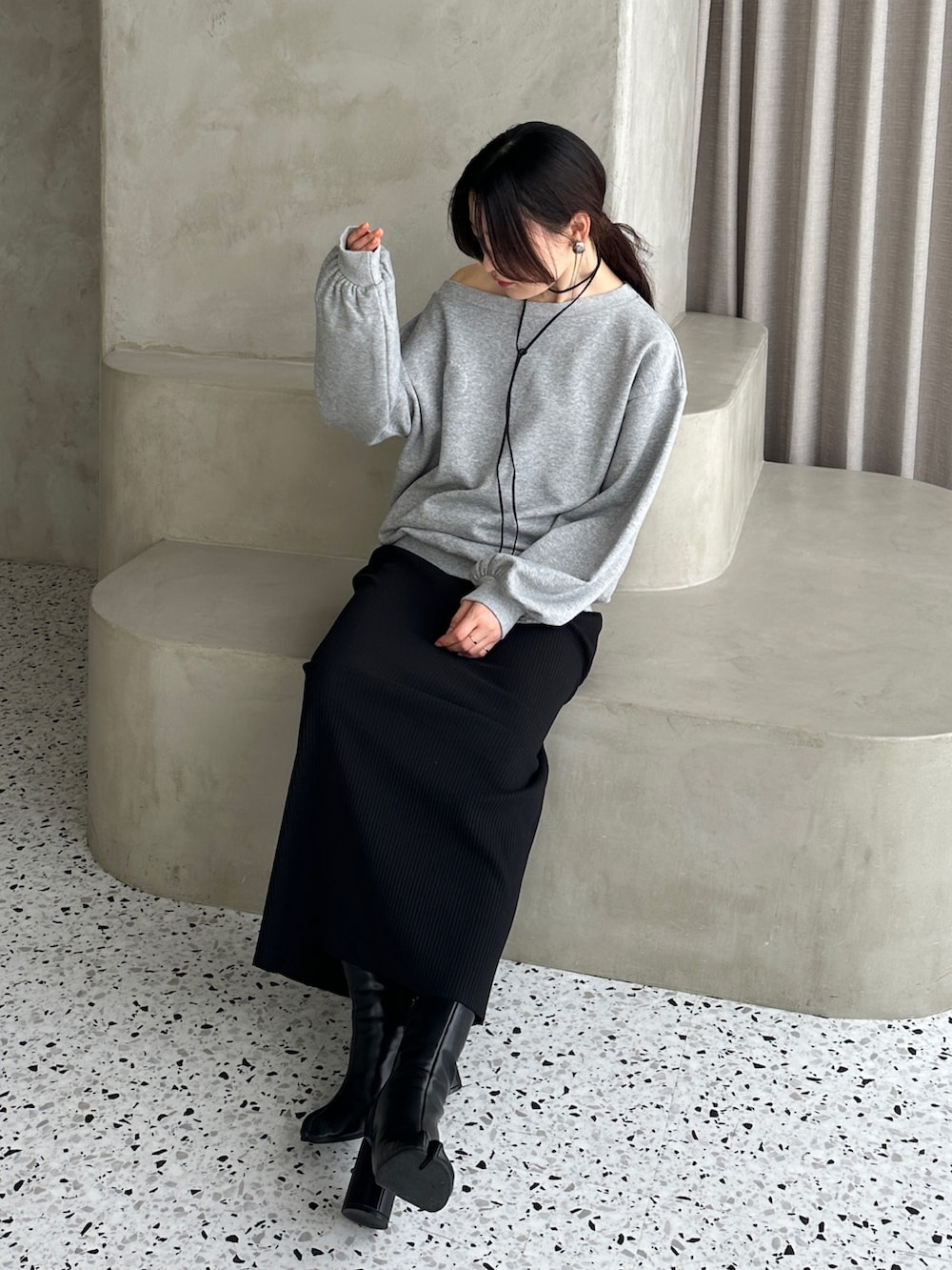グレー系のスウェット、ブラック系のスカート、ブラック系のブーツを着用したレディースの秋コーディネートの3枚目の写真