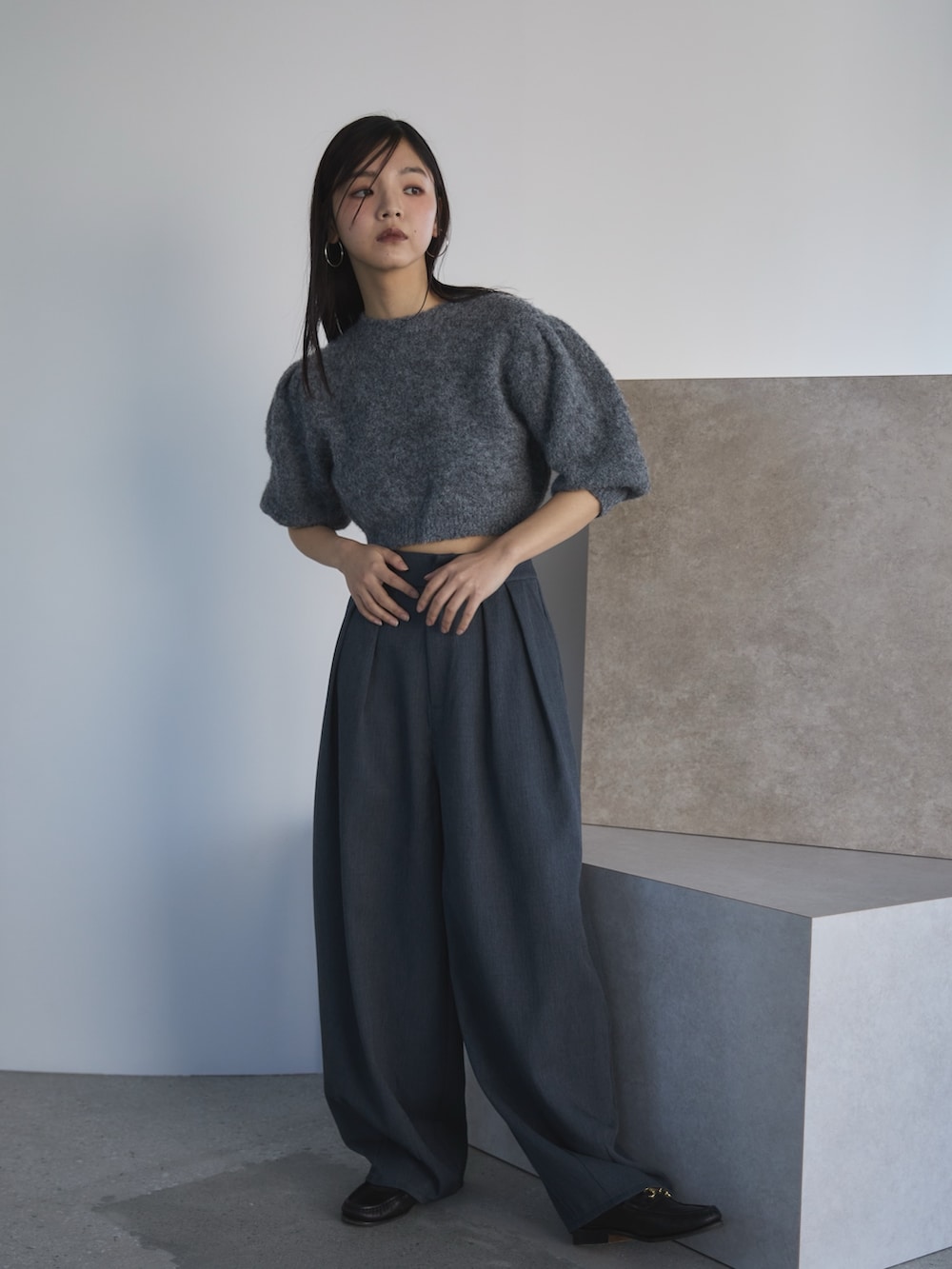 グレー系のニット/セーター、グレー系のスラックス、ブラック系のローファーを着用したレディースの冬コーディネートの3枚目の写真