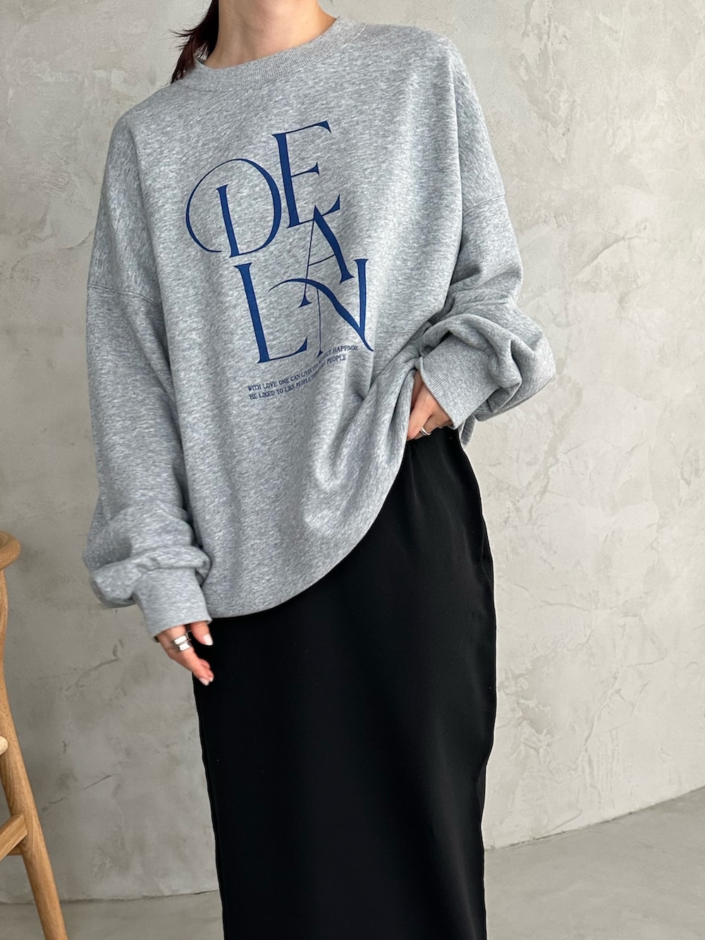 ブラック系のチェスターコート、グレー系のスウェット、ブラック系のスカートを着用したレディースの冬コーディネートの4枚目の写真