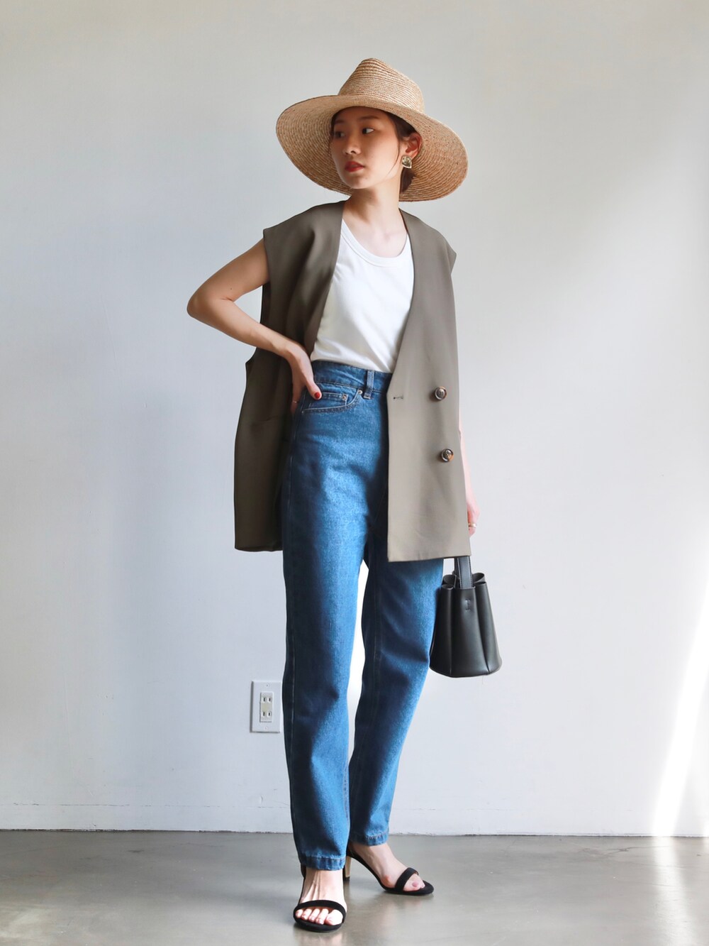 ブラック系のサンダル、ブラック系のショルダーバッグ、ブラウン系のベストを着用したレディースの春コーディネートの2枚目の写真